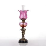 Oil lamp with cranberry glass shade and reservoir on brass stem, on circular base, 70cm high overall