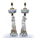 Pair of Continental porcelain figural table lamps depicting ladies holding the faux reservoir aloft,