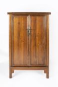 Ming style elm cabinet Chinese, of tapered form with brass lock and with panelled doors, 89cm wide