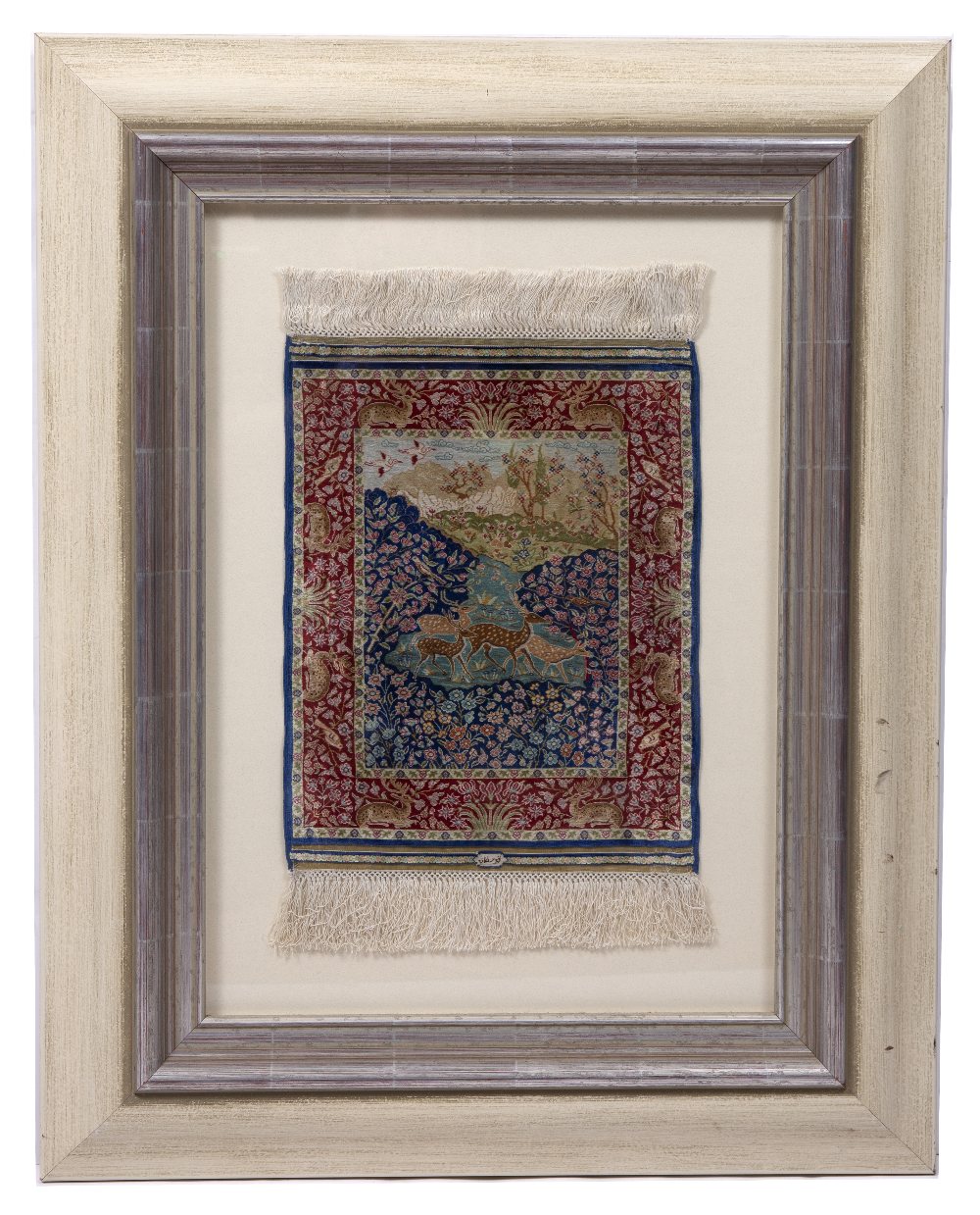 A PERSIAN MINIATURE SILK RUG woven with deer in a landscape pattern in colours within a red border