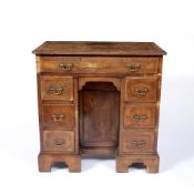 AN 18TH CENTURY WALNUT VENEERED AND FEATHER BANDED KNEEHOLE DESK, fitted with an arrangement of