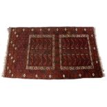 A TURKOMAN WINE GROUND RUG with a central framed hooked motif within a geometric and pine cone