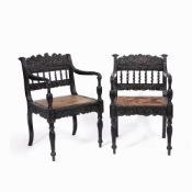A NEAR PAIR OF EARLY 19TH CENTURY CEYLONESE CARVED EBONY OPEN ARMCHAIRS the foliate crest rails over