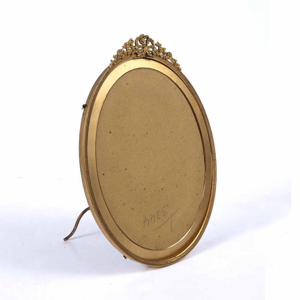 A GILT METAL OVAL PORTRAIT FRAME with ribbon swag cresting and easel support, green velvet back by - Image 2 of 3