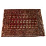 A TEKKE BOKHARA TRIBAL RUG with three rows of ten medallions on a deep red ground and within a