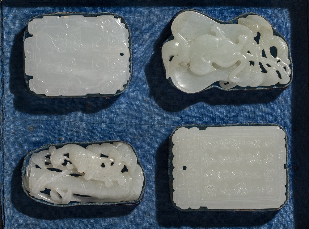 Collection of four white jade pendants Chinese, 18th Century mounted in a black and blue fitted