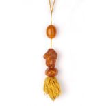 Amber and amber coloured pendants Chinese one in the form of a smiling Buddha, on a string band with