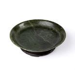 Nephrite jade shallow dish Chinese, 19th Century the dish with raised rim, on a hardwood stand, 25cm