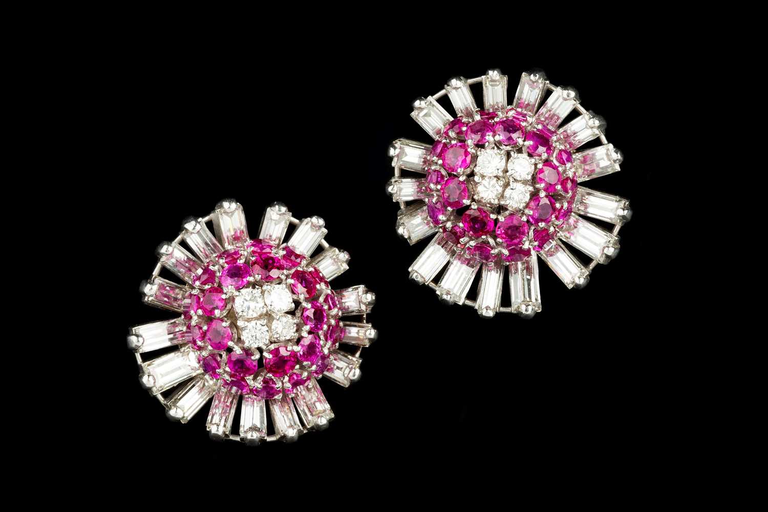 A pair of ruby and diamond cluster ear clips, each designed as a stylized flowerhead, centred with a