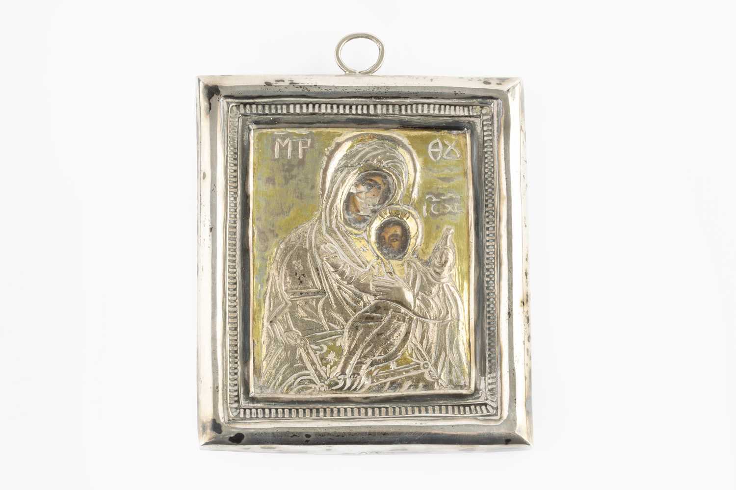 A Greek orthodox silver cased icon, depicting the Madonna and child, with printed faces, on wood