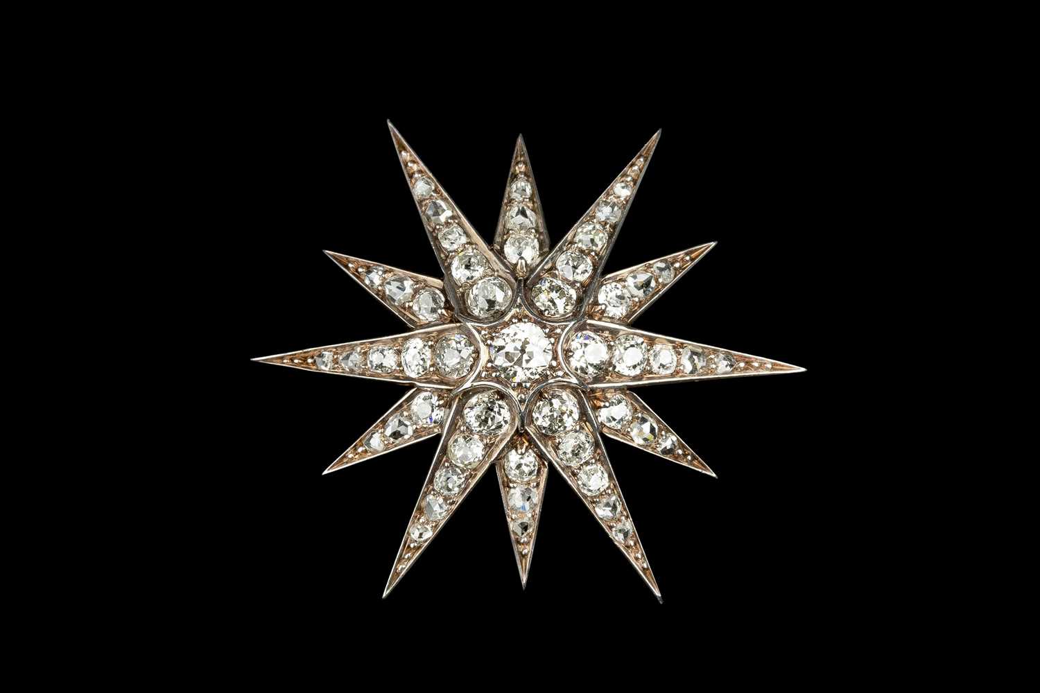 A late 19th/early 20th century diamond star brooch, the principal old-cut diamond bordered by rays