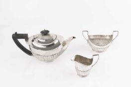 An Edwardian silver bachelor's three piece tea service, with half lobed bodies, the teapot with