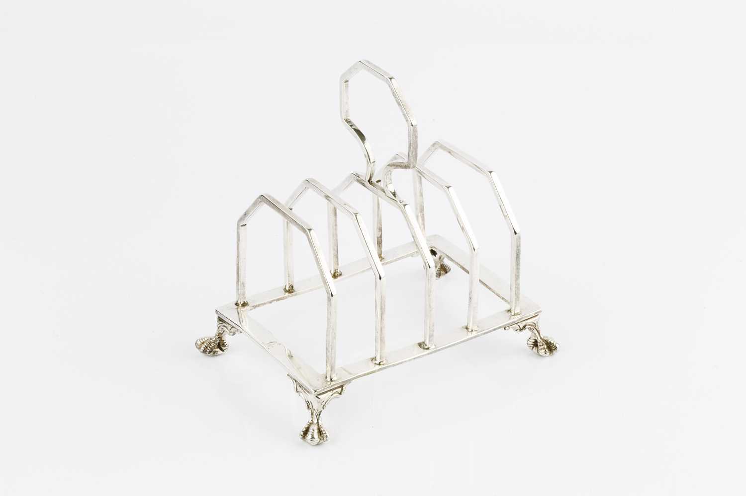 A silver Art Deco style five bar toast rack, with central angular handle, on four claw feet, by