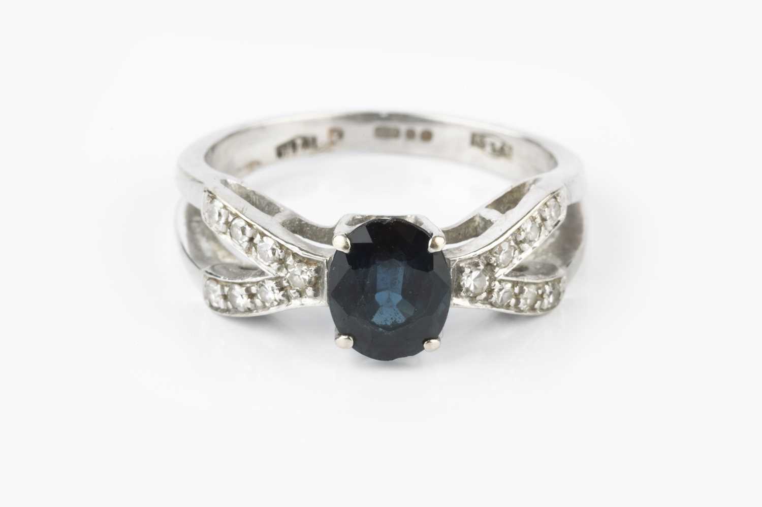 A sapphire and diamond dress ring, the oval mixed-cut sapphire claw set between wishbone-shaped