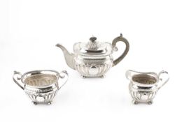 A late Victorian silver three piece tea service, with half lobed and embossed decoration, and