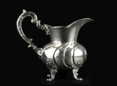 A Peruvian silver water jug, with shaped baluster body, foliate scroll handle, and shaped feet,