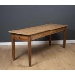 A rectangular pine kitchen table with single frieze drawer to one end, standing on square tapering