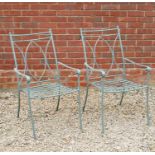 A pair of green painted wrought iron garden armchairs with scrolling arms and slatted seats, 54cm