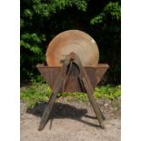 An antique grinding wheel the sandstone wheel in a cast iron trough and on wooden legs, 89cm wide