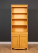 A 20th century yellow painted waterfall bookcase cabinet with a distressed look, three adjustable