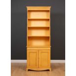 A 20th century yellow painted waterfall bookcase cabinet with a distressed look, three adjustable