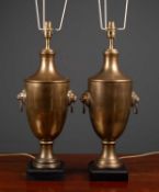 A pair of cast brass table lamps of urn form with lion mask ring handles and black painted square