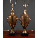 A pair of cast brass table lamps of urn form with lion mask ring handles and black painted square