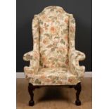 A George II style wingback armchair with floral upholstery and label for 'The Odd Chair Company'