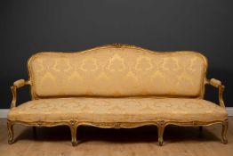 A large French giltwood sofa, the shaped back with floral carved ornament to the cresting rail, with