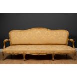 A large French giltwood sofa, the shaped back with floral carved ornament to the cresting rail, with