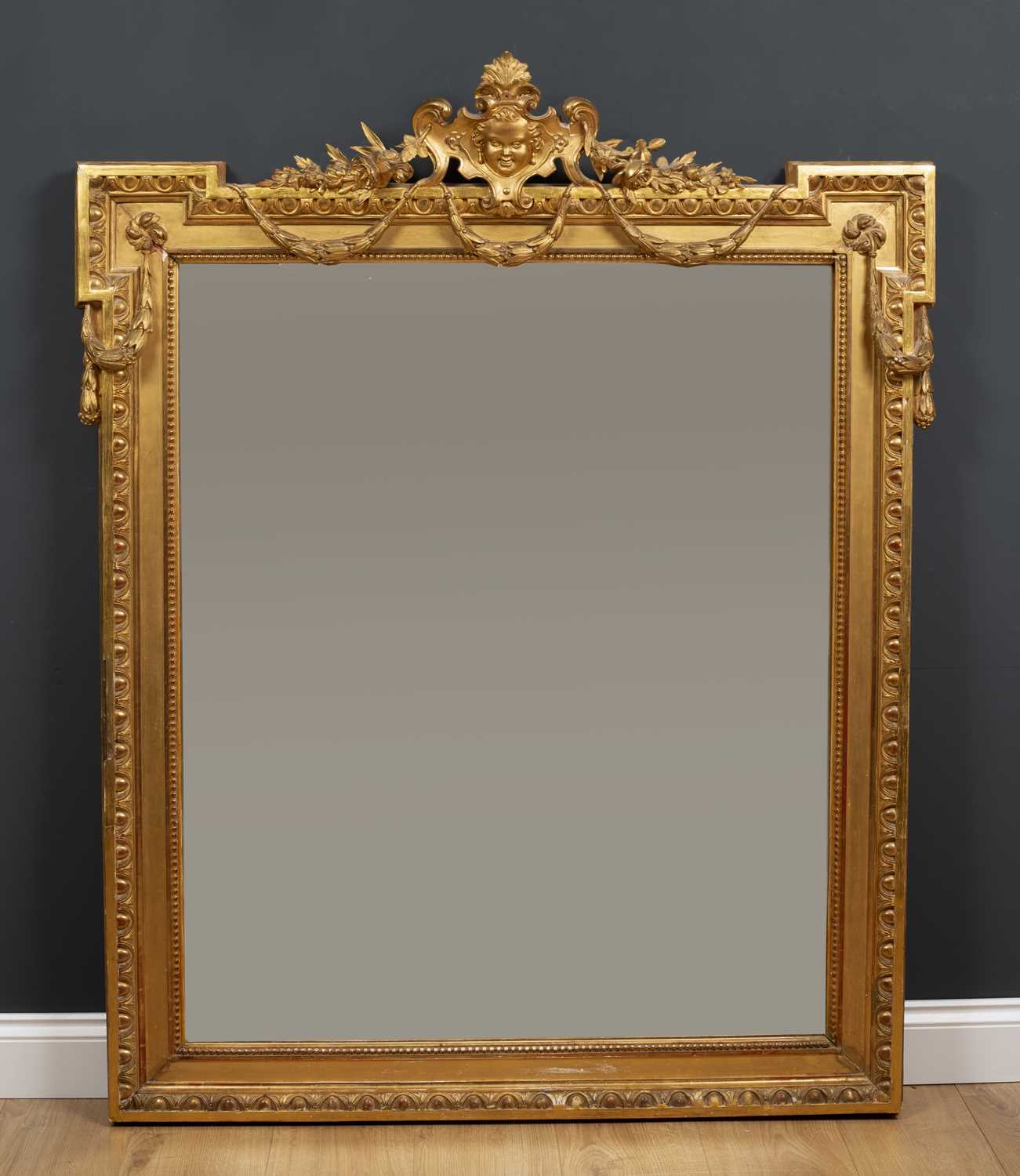 A 19th century gilt wall mirror with outset upper corners and central mask crest with floral and