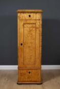 A 19th Century Biedermeier satin birch tall narrow cabinet the single panelled door enclosing