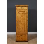 A 19th Century Biedermeier satin birch tall narrow cabinet the single panelled door enclosing