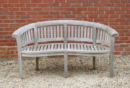A curving teak garden bench with serpentine front, 66cm wide x 66cm deep x 82cm highCondition