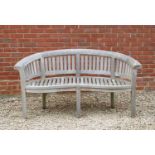 A curving teak garden bench with serpentine front, 66cm wide x 66cm deep x 82cm highCondition