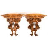 A pair of carved continental satin birch bow fronted wall brackets with scrolling supports, 34cm