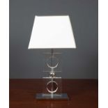 A contemporary glass and white metal plated table lamp with two hollow square sections and on a