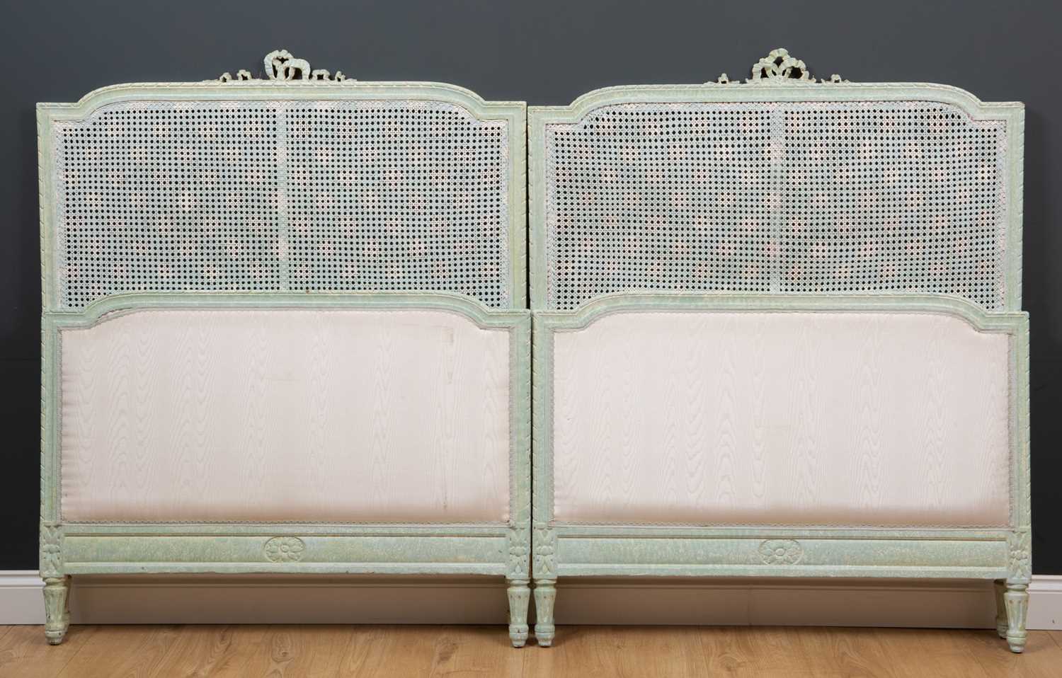 A pair of green painted single beds with caned inset panelsCondition report: One inner caned panel