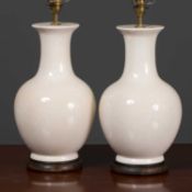 A pair of cream crackle glaze ceramic table lamps with turned wooden socles, 46cm high to the