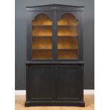 A black painted library cabinet the upper section with gold painted interior with adjustable shelves
