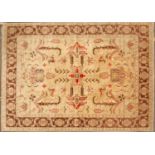 An Oriental dark cream ground small carpet with stylized foliate motifs to the central field and