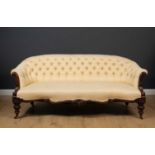 A 19th century mahogany framed cream button upholstered sofa with serpentine front, scrolling arm