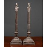 A pair of silvered table lamps in the form of a classical Corinthian column on a stepped plinth