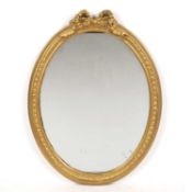 An oval gilt framed wall mirror with ribbon tied crest, 53cm wide x 71cm highCondition report: Minor