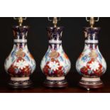 A set of three porcelain table lamps decorated in Imari colours and on turned socle bases, each