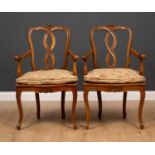 A pair of continental walnut open armchairs with caned seats and cabriole legs, each 60cm wide x