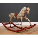 An old small size wood and cloth rocking horse with leather saddle on a red painted base, bearing