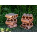 A group of eight Italian terracotta extruded bottle stands possibly stacked as a sculptural element,