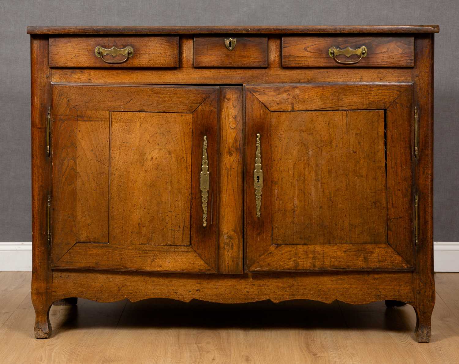 An early 19th century French oak and walnut side cabinet with three drawers above two doors, with