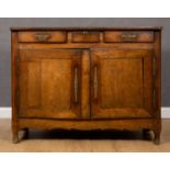 An early 19th century French oak and walnut side cabinet with three drawers above two doors, with